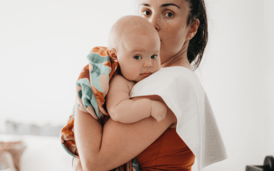 baby on moms shoulder with burp cloth 
